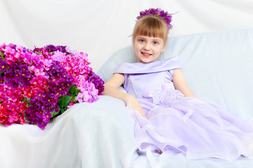 Girl sits next to a bouquet of flowers.