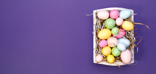 Multicolor eggs in a white tray. Creative Easter concept. Modern solid ultra violet  background.