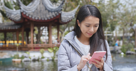 Woman use of smart phone in chinese garden