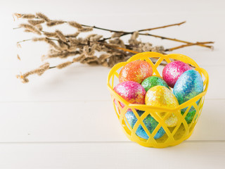 Basket with colorful eggs on a white rustic table.