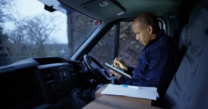 4K Handsome delivery driver sitting in the cab preparing packages for delivery