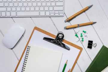 Wooden White office desk table with cup of coffee, Notebook, Pen on it.