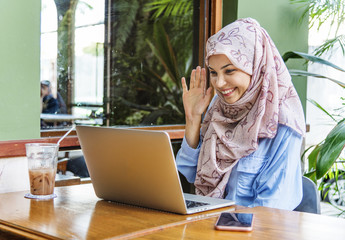 Islamic woman using laptop foe video call with happy face