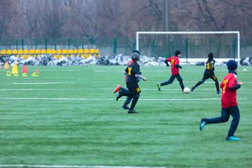 boys play football on the winter stadium