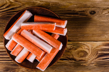 Ceramic plate with crab sticks on wooden table. Top view