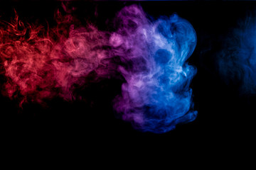 Dense multicolored smoke of blue, red and purple colors on a black isolated background. Background of smoke vape
