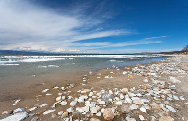 Lake Baikal on a spring day. Sandy coast of Olkhon Island during the melting of ice