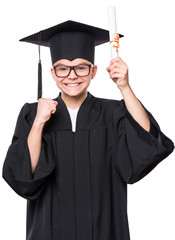 Portrait of graduate teen boy student in black graduation gown with hat and eyeglasses, holding diploma - isolated on white background. Lucky cheerful schoolboy celebrating triumph.