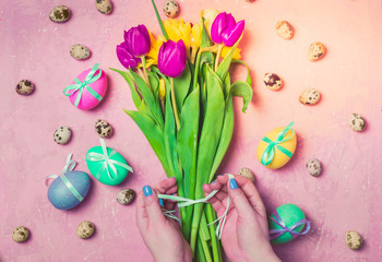 Female hands making spring tulips and daffodils bouquet. Easter composition with flowers and eggs