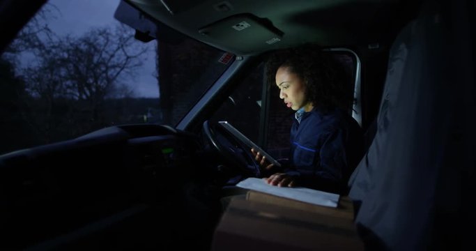 4K Female delivery driver with bad attitude sitting in van checking parcels for delivery. Slow motion.
