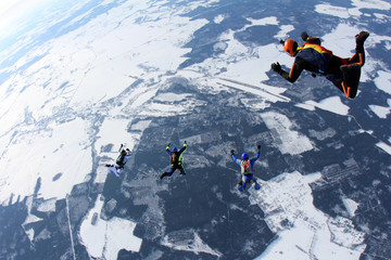 Skydivers are in the winter sky.