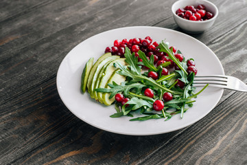 Healthy salad with arugula, avocado and berries