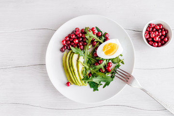 Healthy salad with arugula, avocado and berries and egg