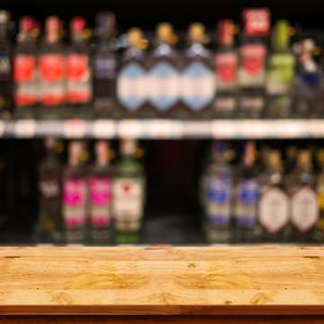 Empty top of wooden table with blurred counter bar and bottles Background.