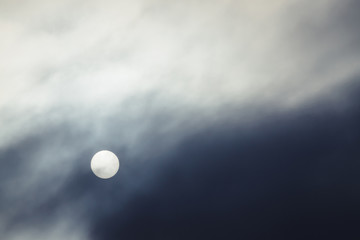 Cold sun shines through thick fog in overcast weather.