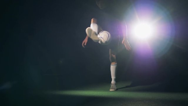 Soccer footbal player silhouette. Professional football player practicing with the ball in dark.