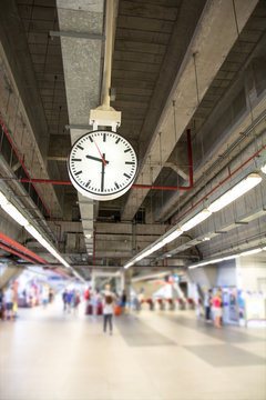 clock is hanging on the steel arch roof structure at train station,