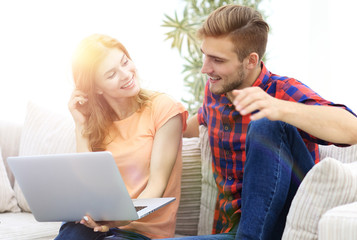 young man and his girlfriend looking at pictures on the laptop.