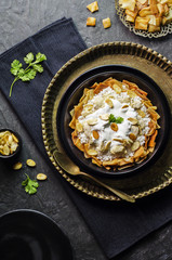 Arabic cuisine; Jordanian Chicken Mansaf of white rice and crispy fried bread topped with chunks of chicken,garlic yogurt sauce and toasted almond on dark plate. Top view with close-up