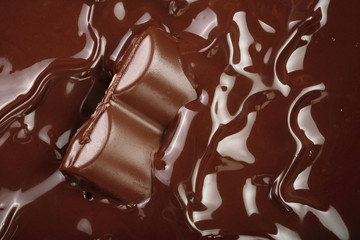 Melted chocolate and pieces of chocolate bar as a background closeup