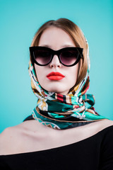 Fashion portrait stylish pretty woman in sunglasses posing against blue background.