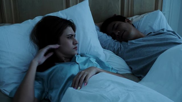 Young woman is disturbed sleep from the sound of snoring