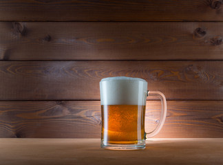 Glass of golden beer on wooden background