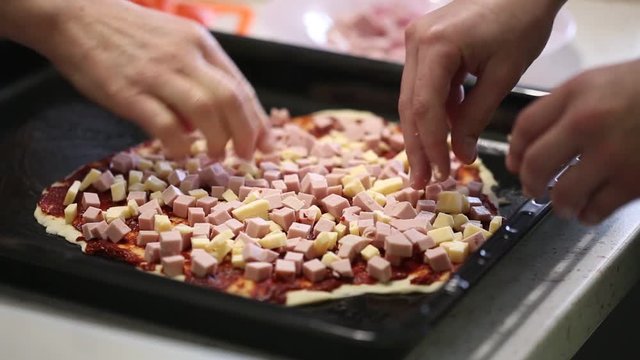 children's hands prepare pizza. spread the filling on the dough.