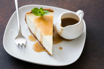 Cheesecake with caramel sauce on white plate, closeup view, selective focus. Slice of cheesecake, caramel cake
