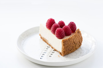 Isolated Slice of Cheesecake with fresh raspberries on white plate