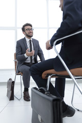 man sitting on chair in office listening to business businessman