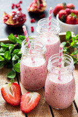 Strawberry pomegranate smoothies on wooden tray. Selective focus. Cleansing, vegan, vegetarian, summer detox concept