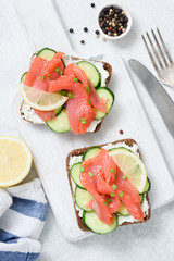 Smoked salmon, cream cheese and cucumber toast sandwiches on white. Top view