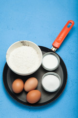 Ingredients for pancakes and fritters in a frying pan.