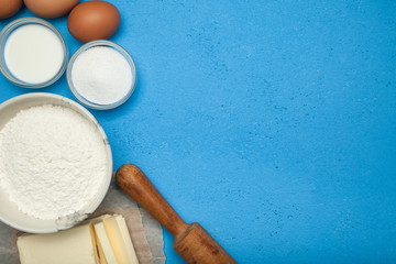 Ingredients for cooking: sugar, eggs, flour and oil on a blue background. Copy space.