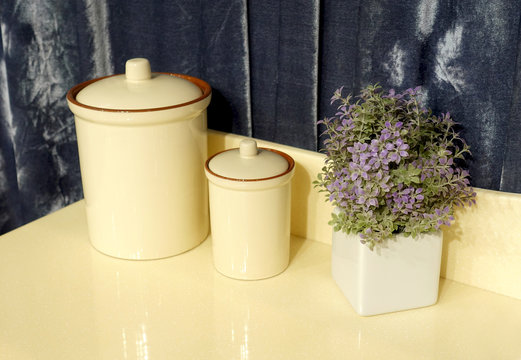 Beautiful beige ceramic jars and flower on the kitchen countertop