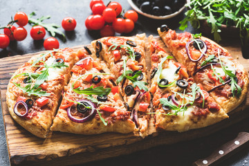 Homemade flatbread pizza sliced on wooden cutting board. Selective focus