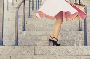 A girl in a skirt spins on stairs with paper packages