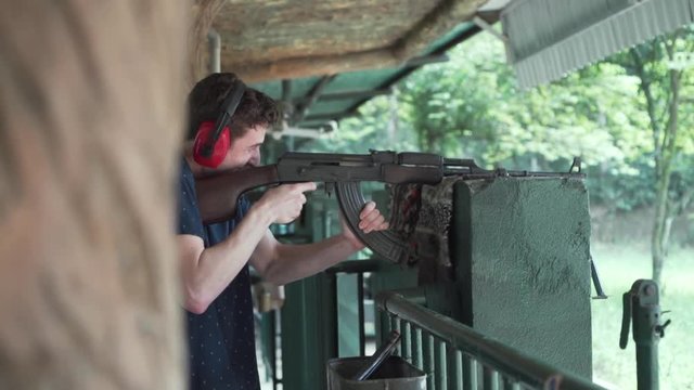 Excited young white male fires machine gun at shooting range at Cu chi tunnels in Vietnam.