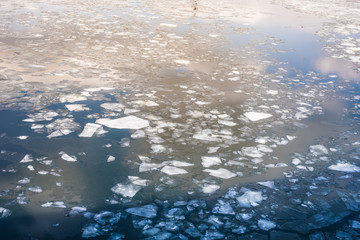 Broken ice on a river in the spring with a reflection of the sun