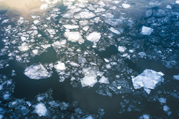 Broken ice on a river in the spring with a reflection of the sun