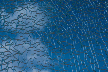 Blue sky with clouds behind broken glass with beautiful cracks