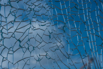 Blue sky with clouds behind broken glass with beautiful cracks