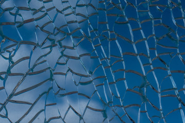 Blue sky with clouds behind broken glass with beautiful cracks