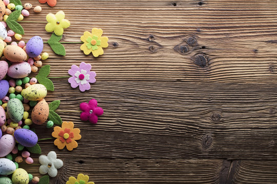 Easter background. Rustic wooden table. Tulips and spring flowers. Easter eggs. Colorful bokeh. Place for typography. 