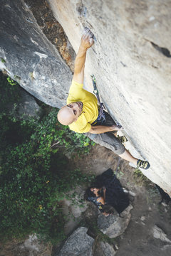 High angle view of climber reaching across for handhold on rock face in limestone wall