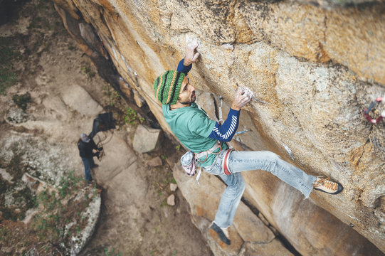 High angle view of climber reaching across for handhold on rock face in granite wall