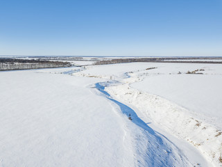 Obraz premium Small frozen river. Ice and snow. Aerial view winter sunny landscape