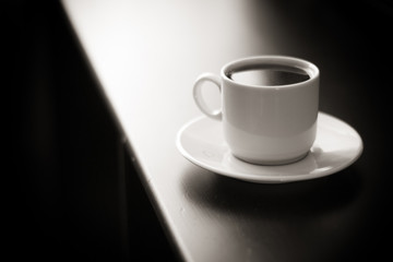 Cup of strong coffee on black table black and white photo