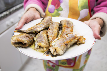 Woman with plate of fried fish, hake